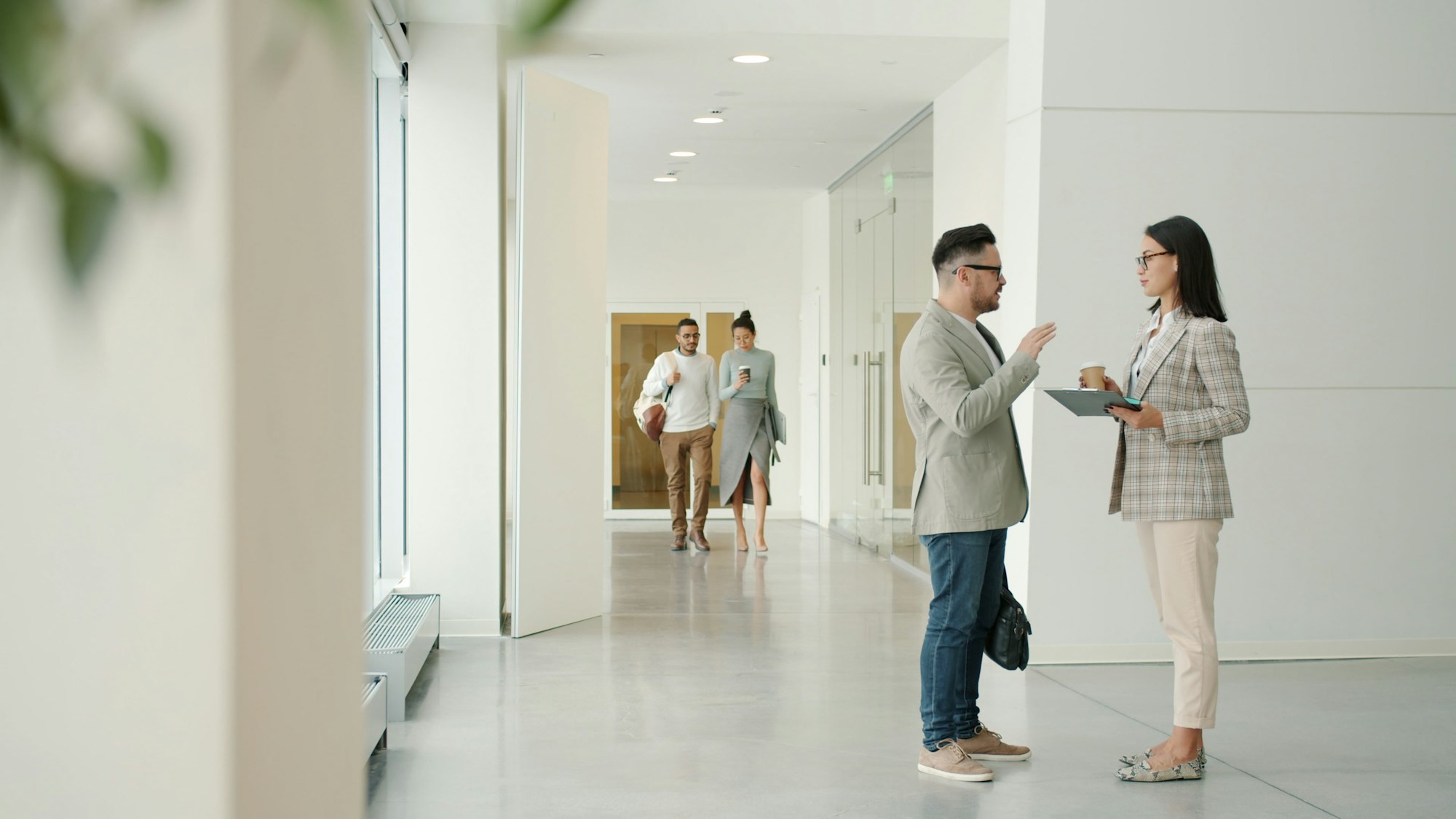 Colleagues talking in a modern office hallway